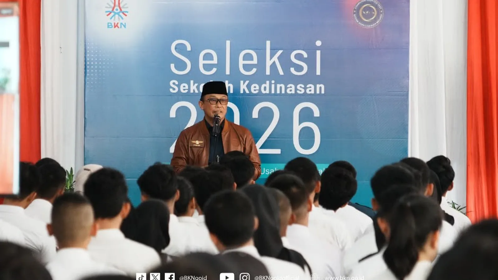 Peserta seleksi sekolah kedinasan 2026 mendengarkan pengarahan di depan spanduk Seleksi Sekolah Kedinasan 2026